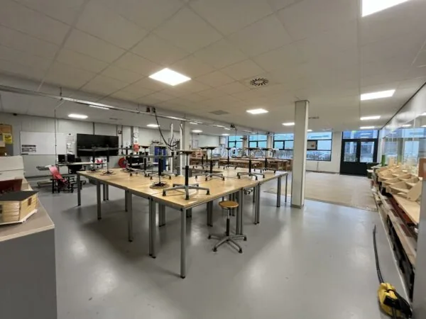 Ruim lokaal met werkbanken, opgestapelde krukken en diverse houtbewerkingsprojecten aan de Niels Bohrweg.